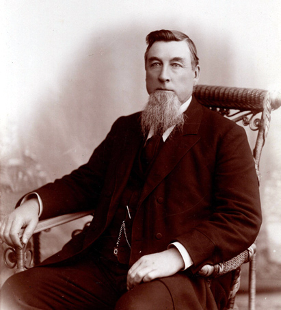Portrait of Donald Grant, seated in a wicker chair.
